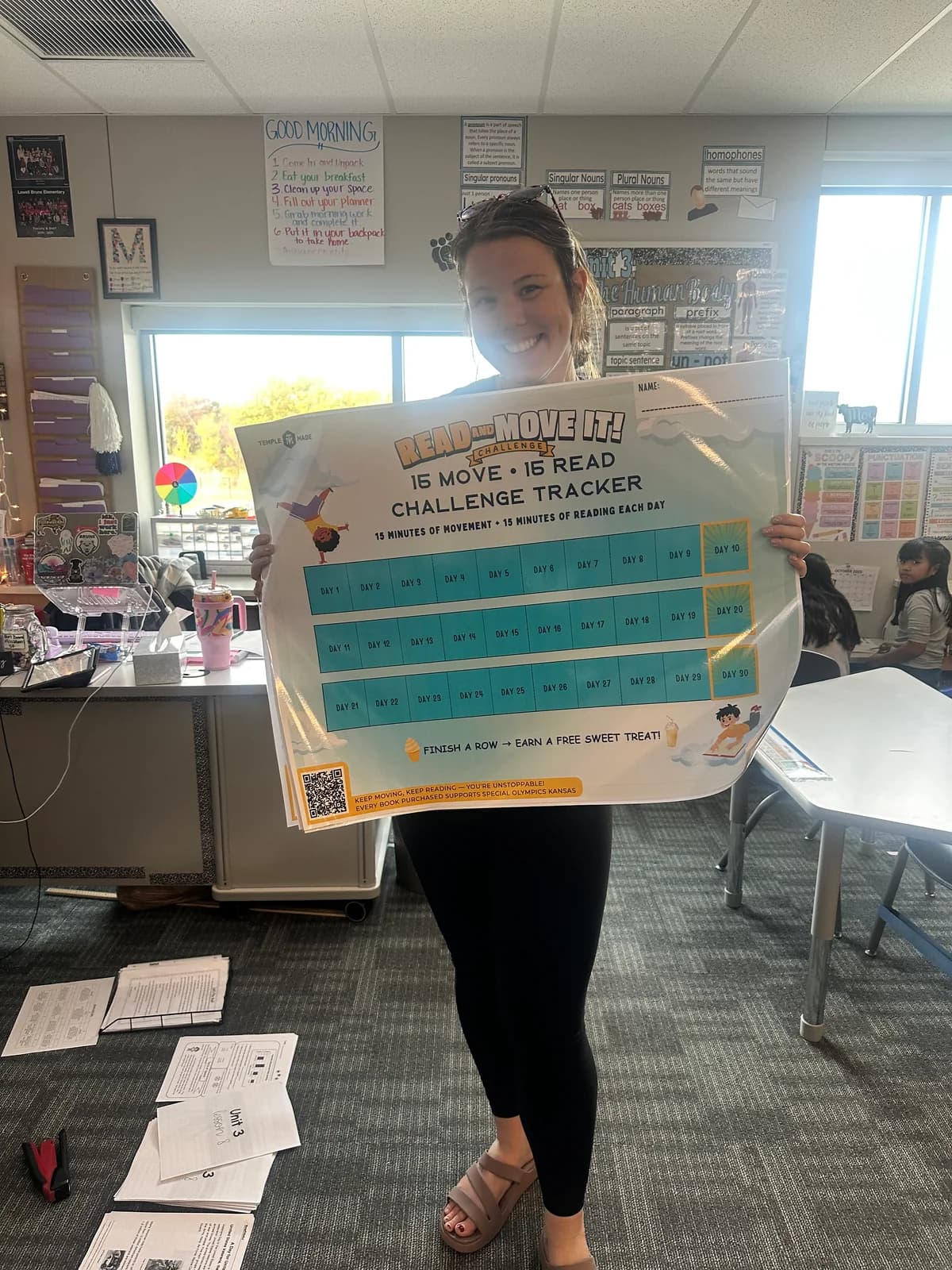 A school staff member holding a Read and Move It challenge certificate