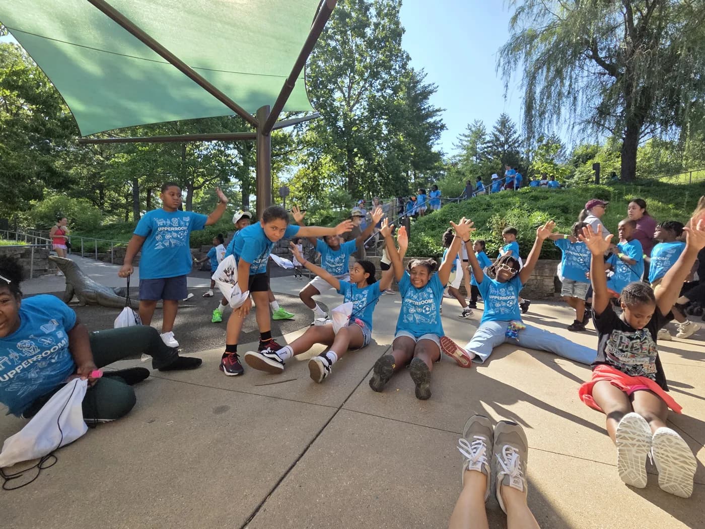 Children in blue program shirts celebrating outdoors at the Kansas City Zoo