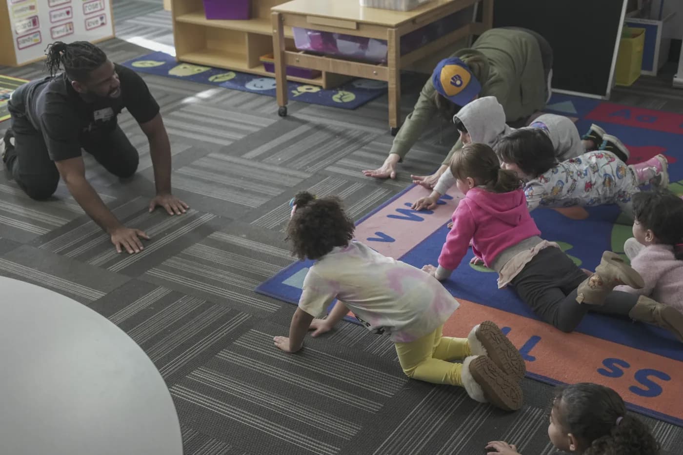 Children and adults practicing floor movements together in a Lawrence classroom
